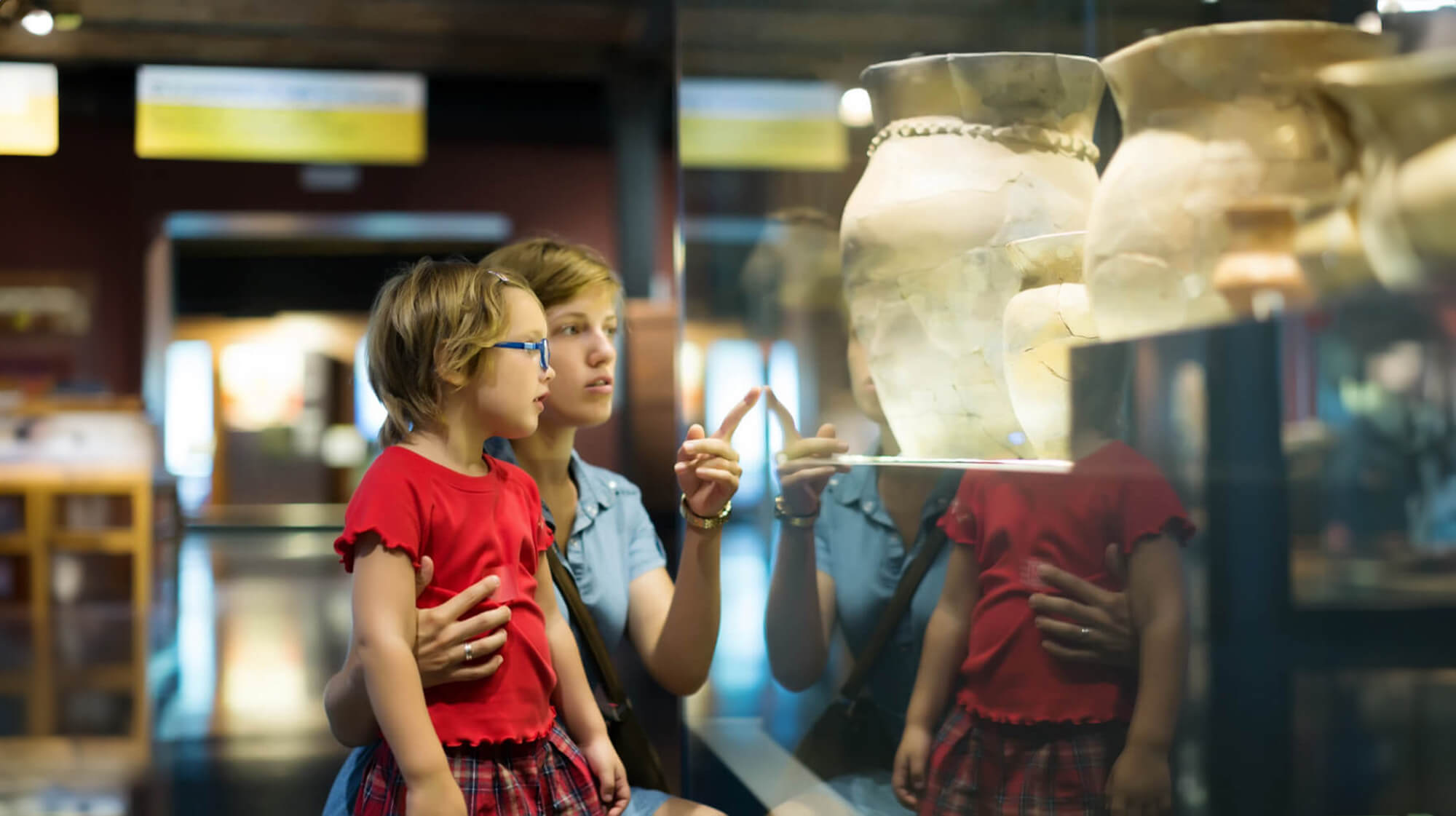 mother and her daughter are looking at
      pottary in the museum